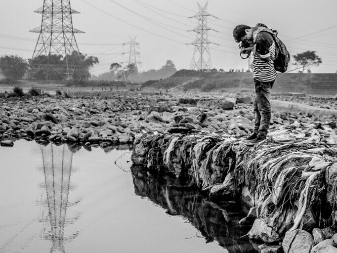 Photo en noir et blanc d’un photographe prenant des photos de monticules de déchets